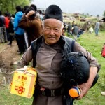 elder man smiles hold food and sleeping bag