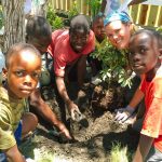 woman and children smile planting